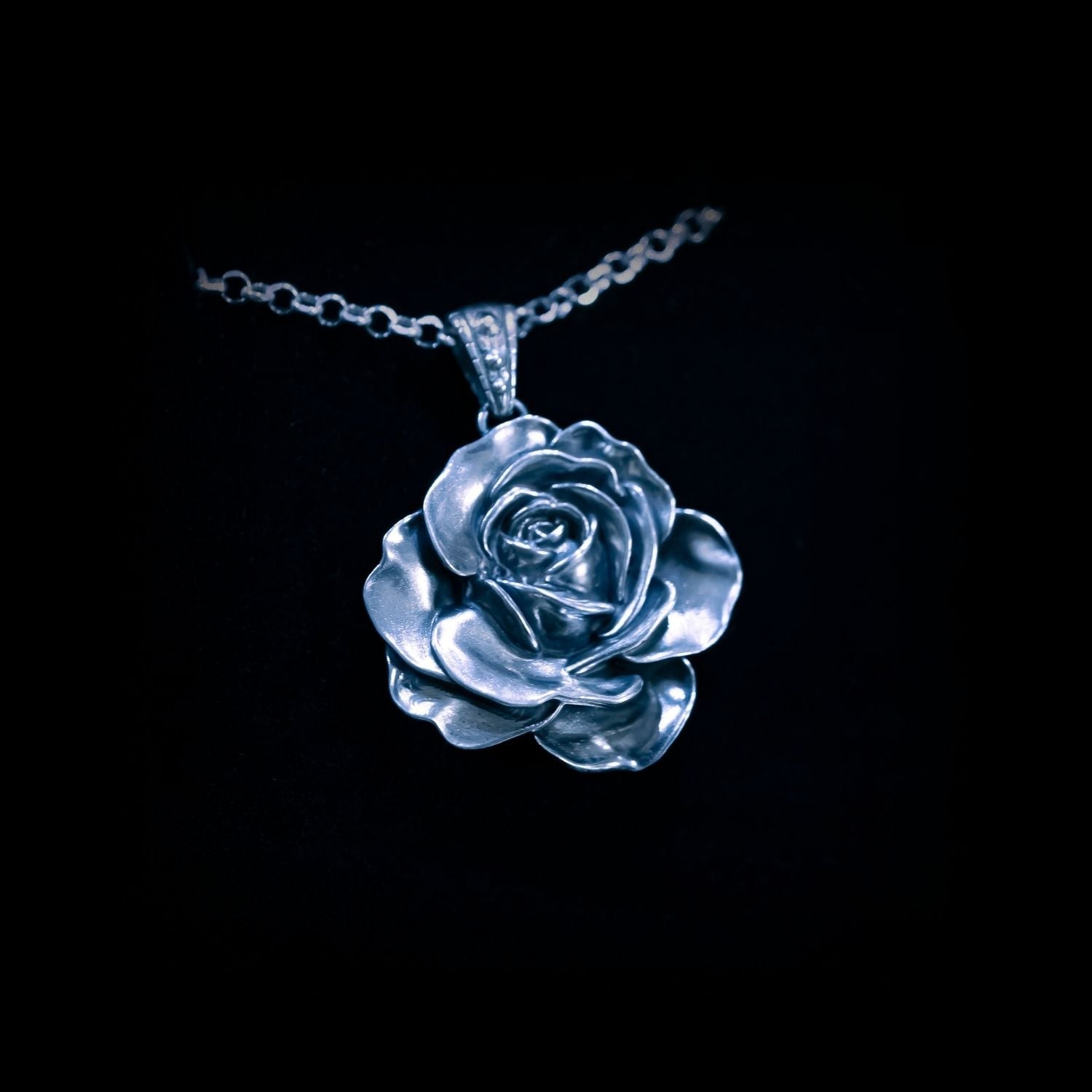Silver rose pendant on a black background