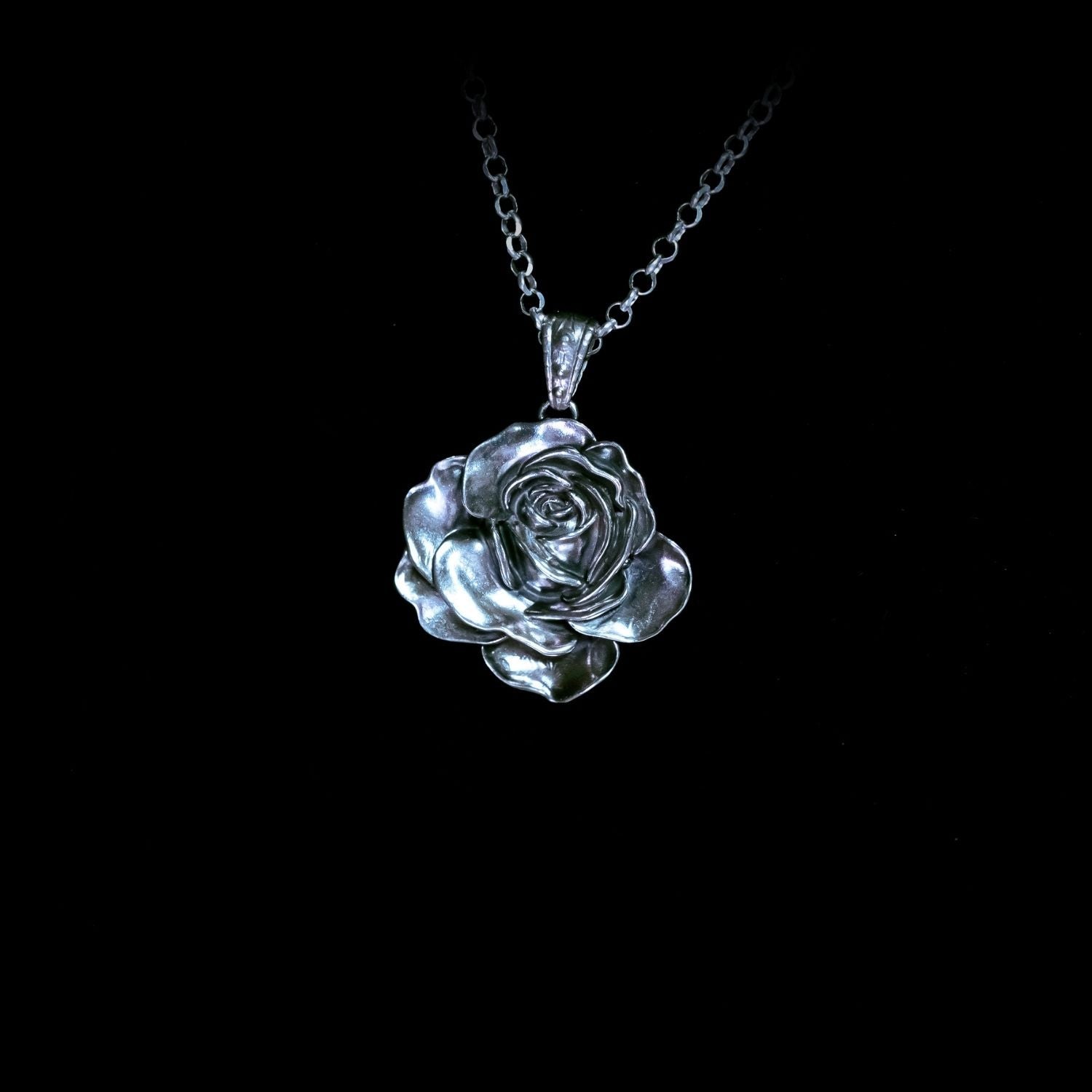 Silver rose pendant necklace on a black background
