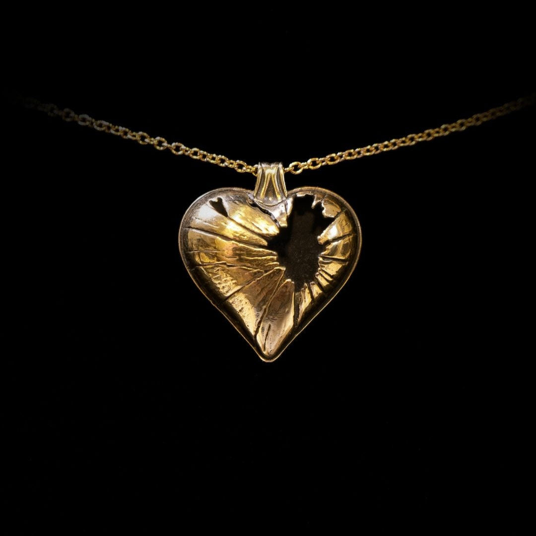 Gold heart-shaped pendant necklace on a black background