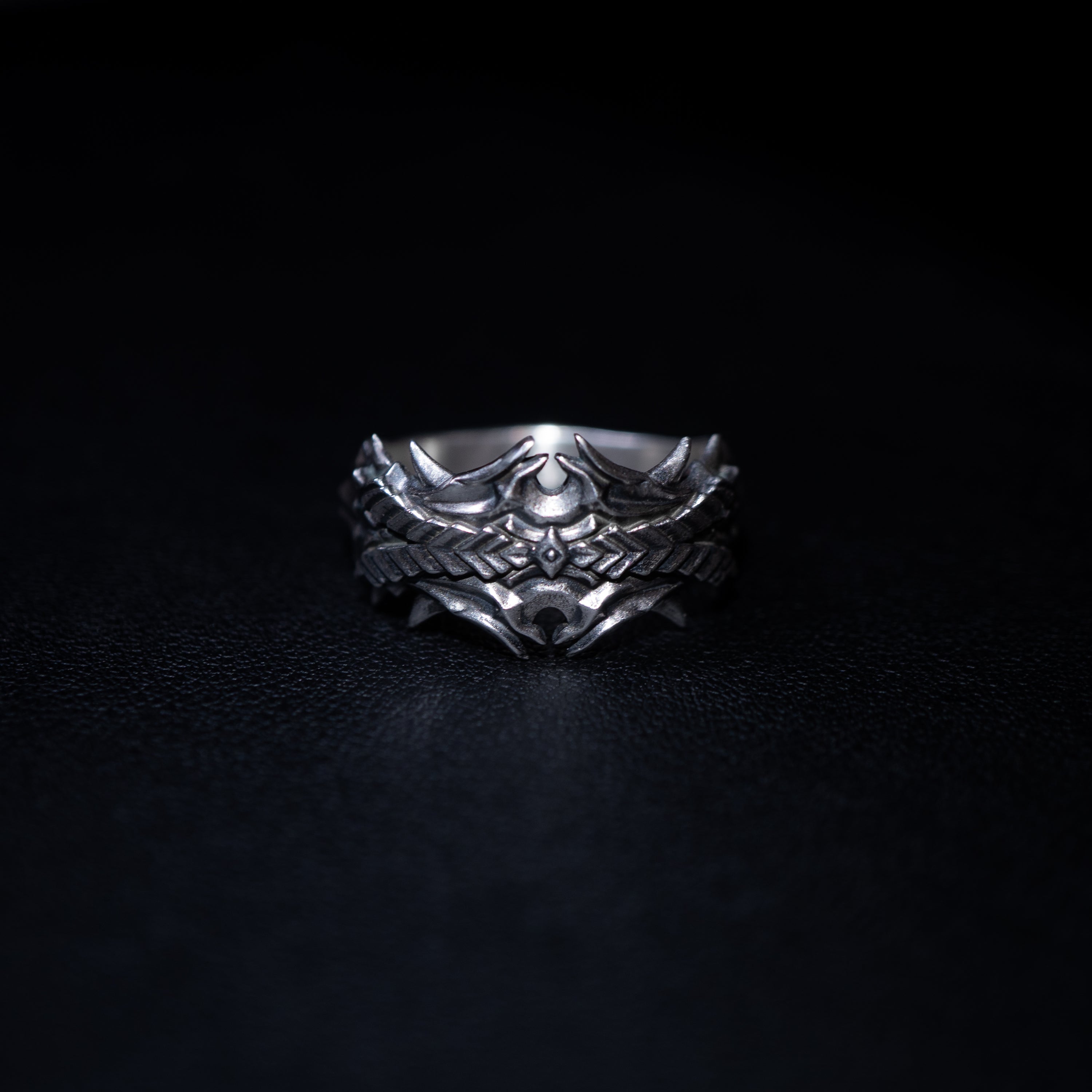 Silver ring with intricate design on a black background