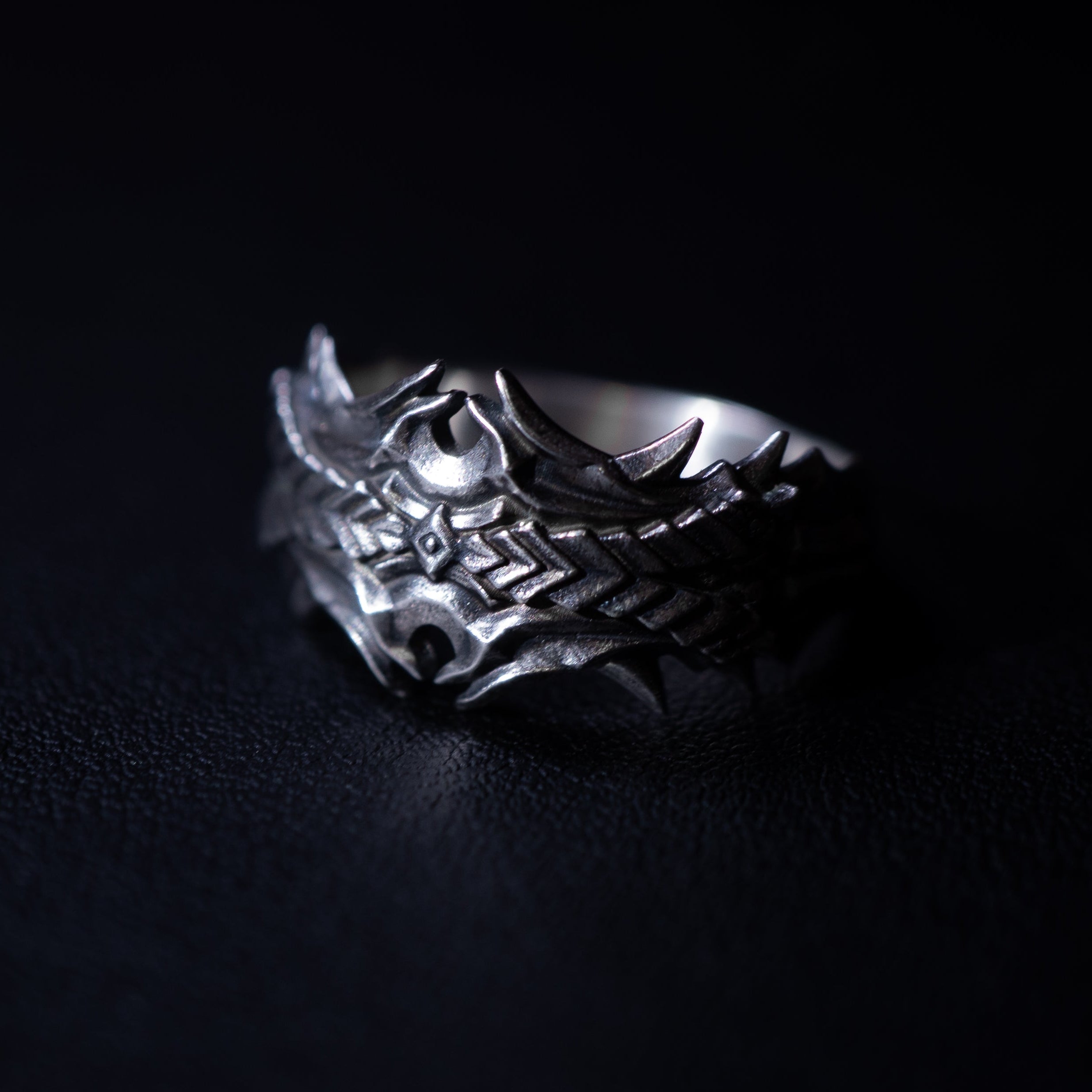 Silver ring with intricate design on a black background