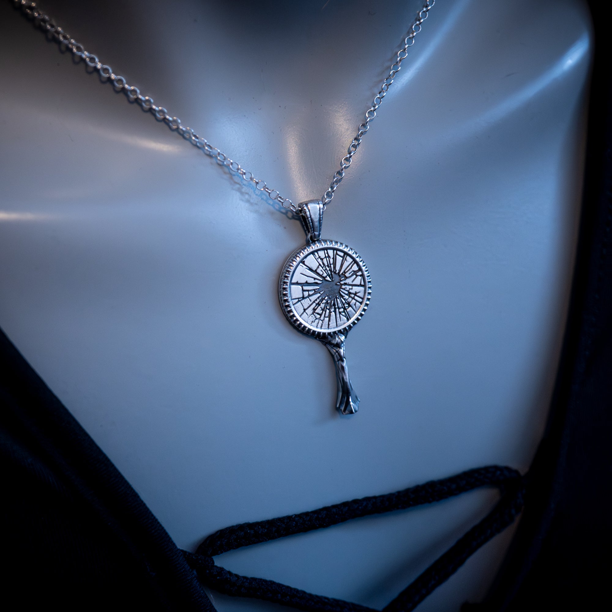 Silver broken mirror necklace with a pendant on a mannequin bust.