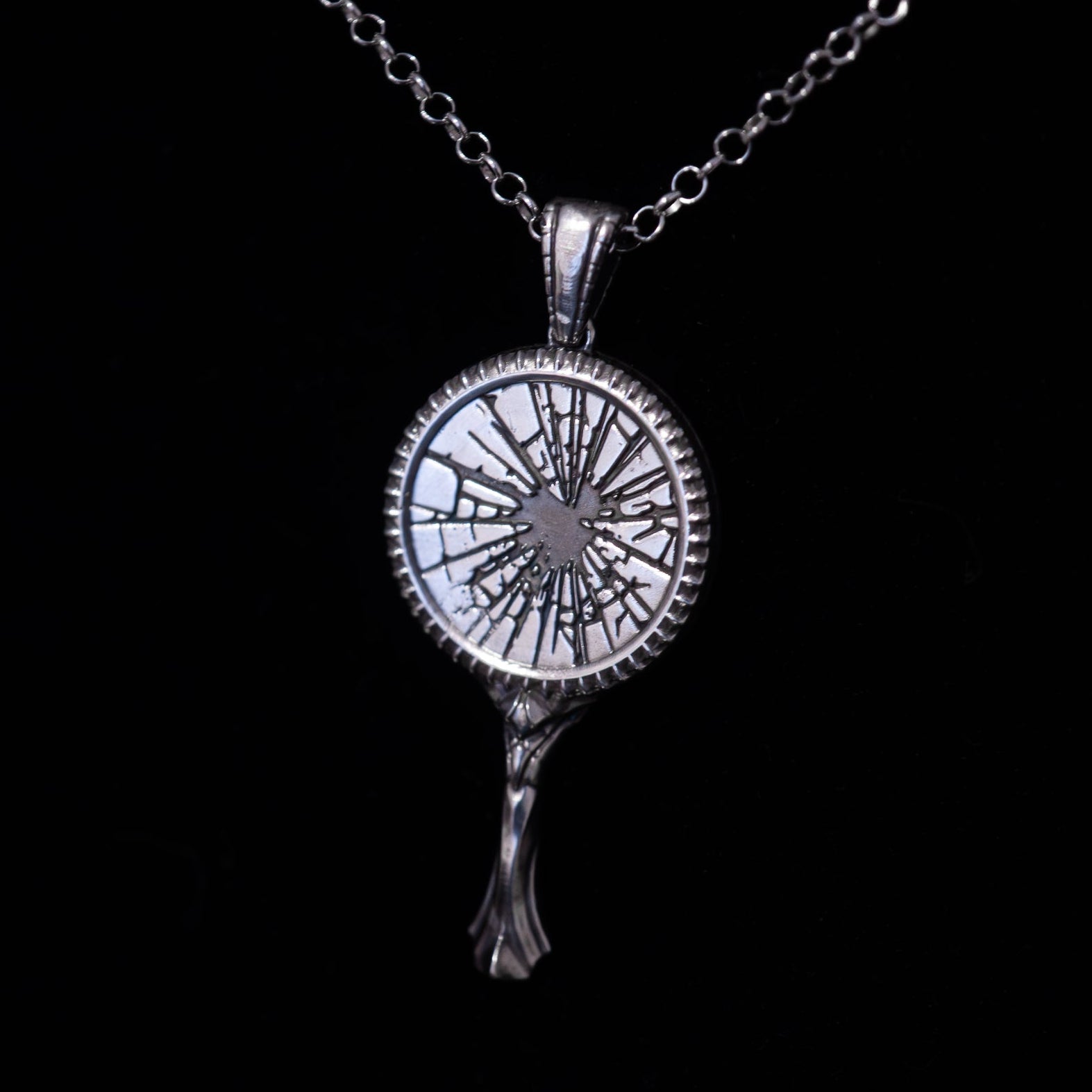 Silver broken mirror pendant necklace on a black background