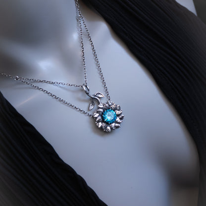 Silver necklace with a blue gemstone pendant on a mannequin bust.