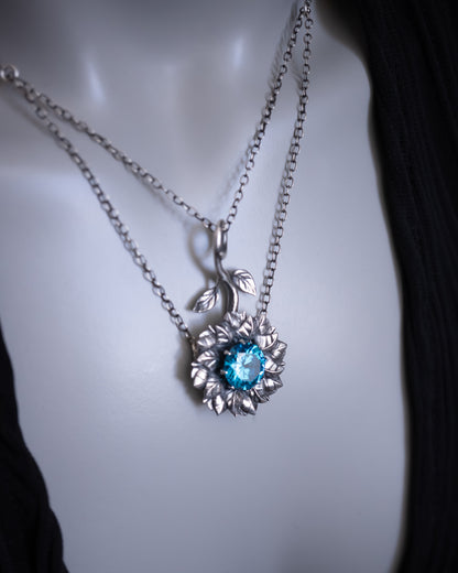 Silver necklace with a blue gemstone pendant on a mannequin.