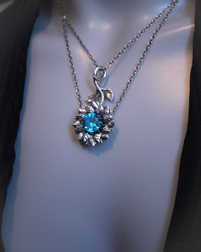 Silver necklace with a blue gemstone pendant on a mannequin.
