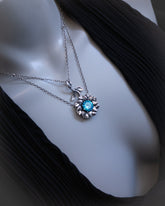 Silver necklace with a blue gemstone pendant on a mannequin bust.