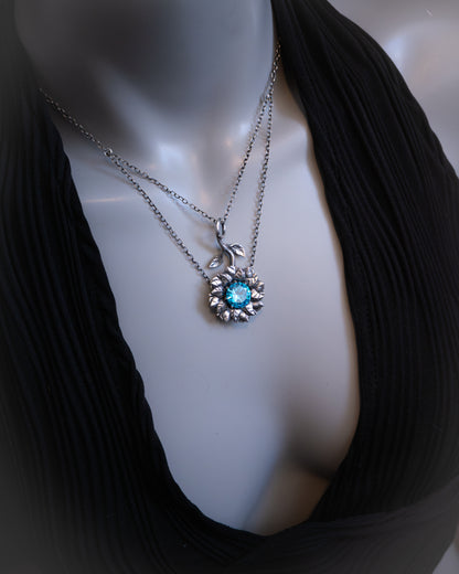 Mannequin wearing a black top with a silver necklace featuring a blue gemstone.