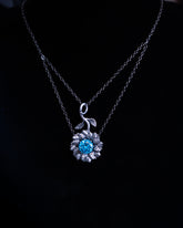Silver necklace with a blue gemstone pendant on a black background