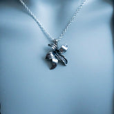 Silver necklace with a leaf-shaped pendant on a light gray background