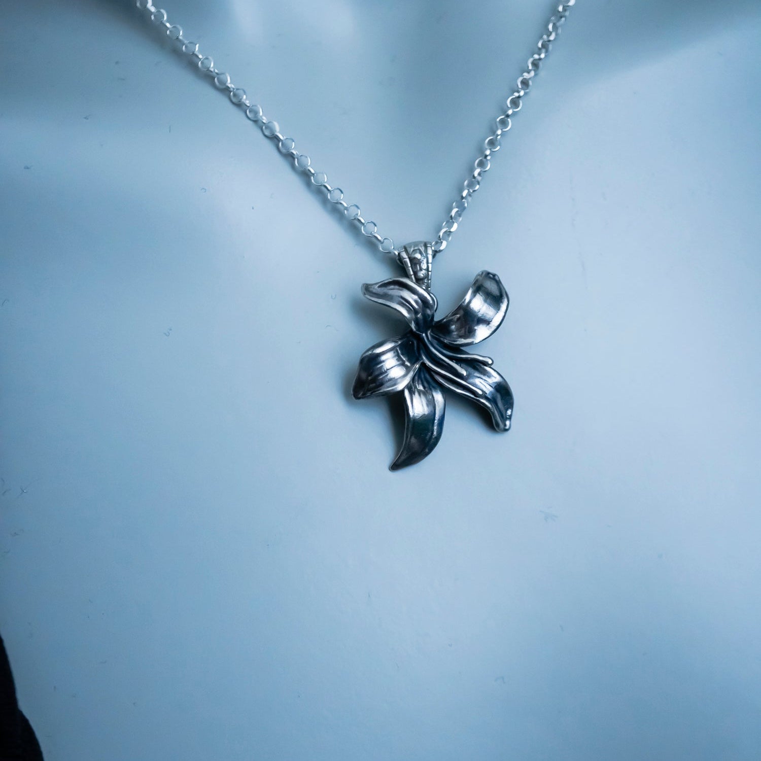 Silver necklace with a leaf-shaped pendant on a mannequin.