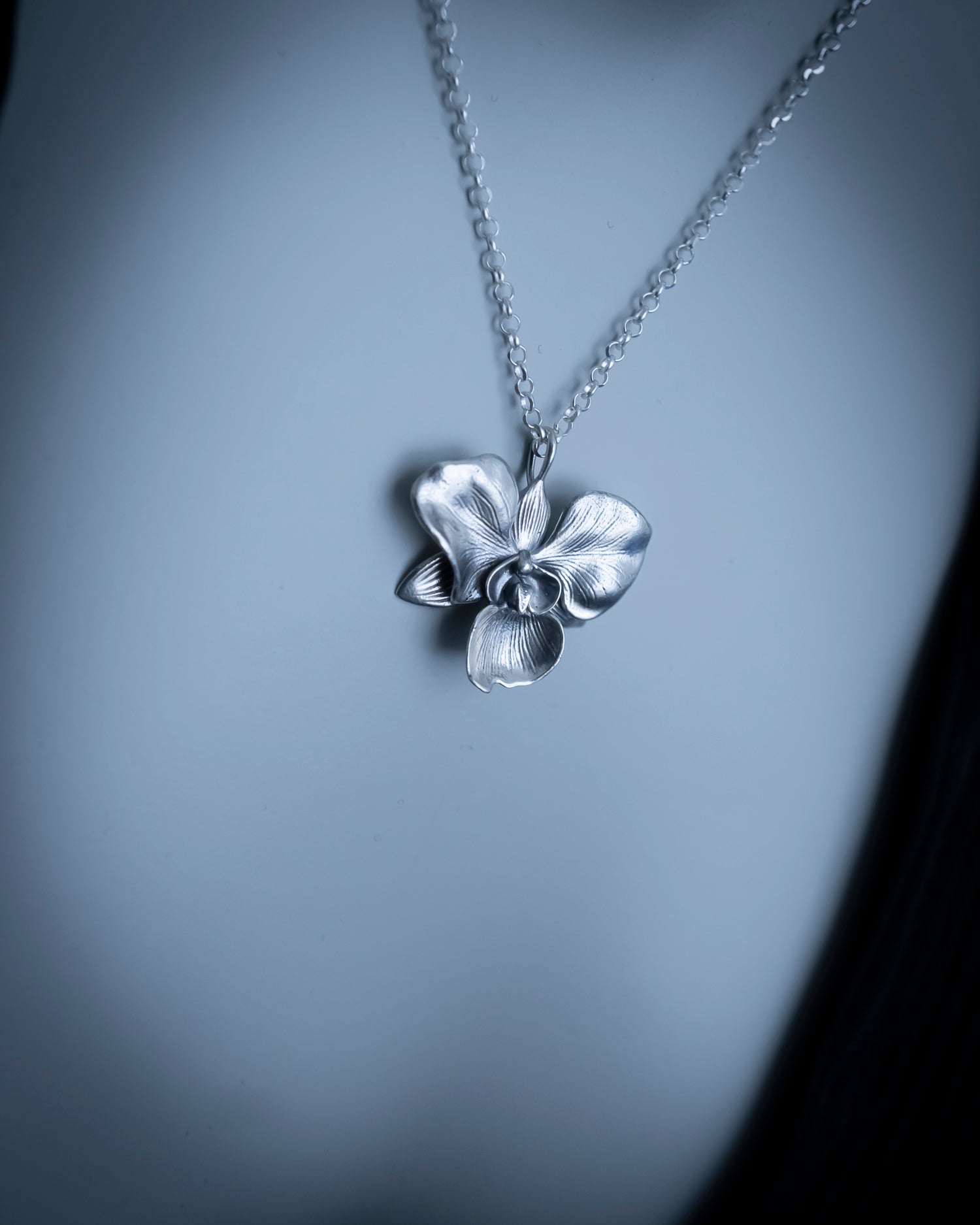 Silver flower pendant necklace on a gray background
