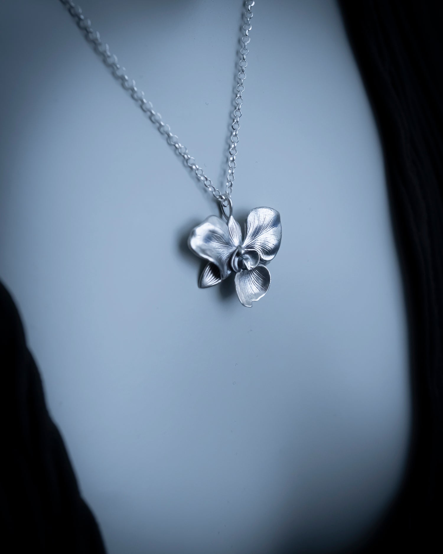 Silver necklace with a floral pendant on a blurred background