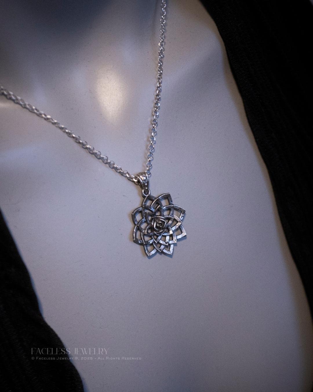 Silver necklace with a intricate pendant on a mannequin.