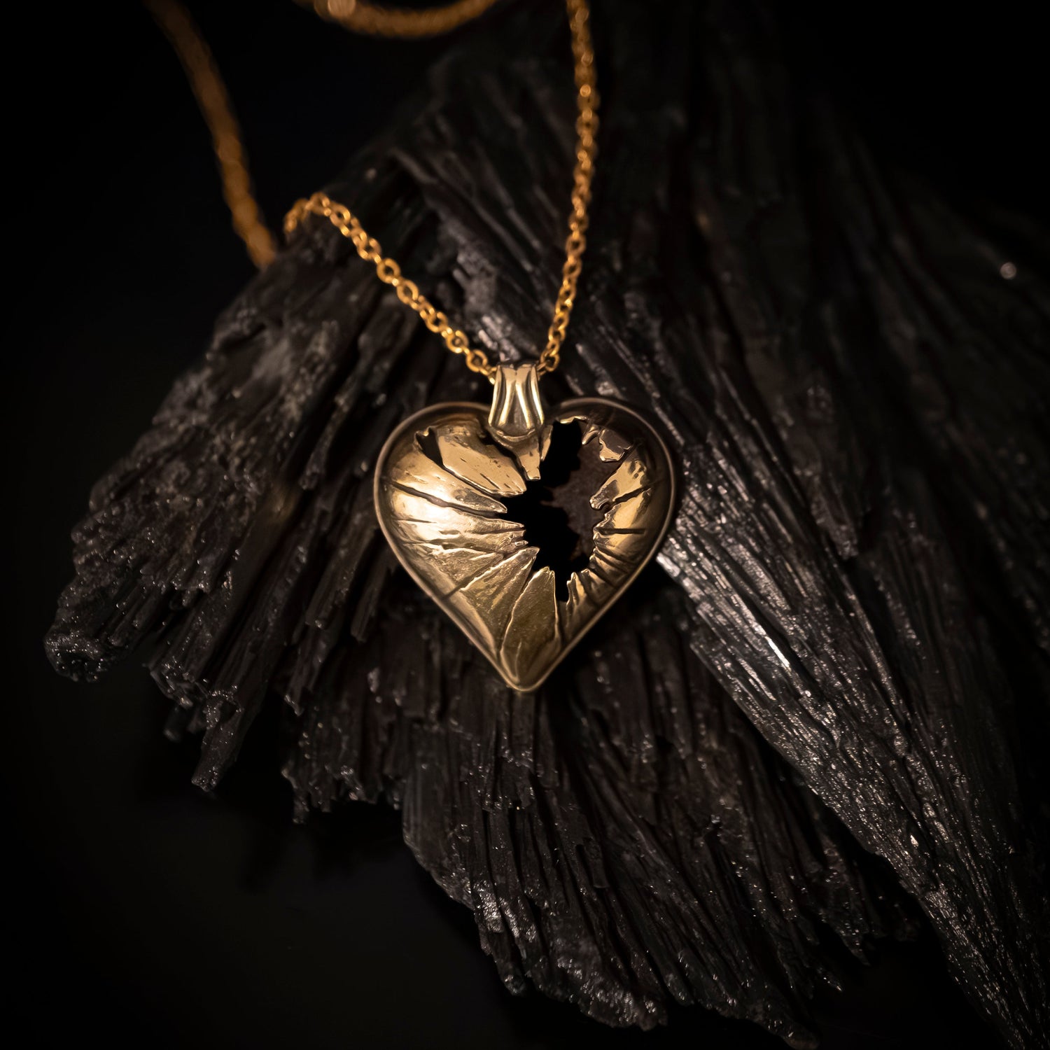Gold heart-shaped pendant with a dark center on a dark background