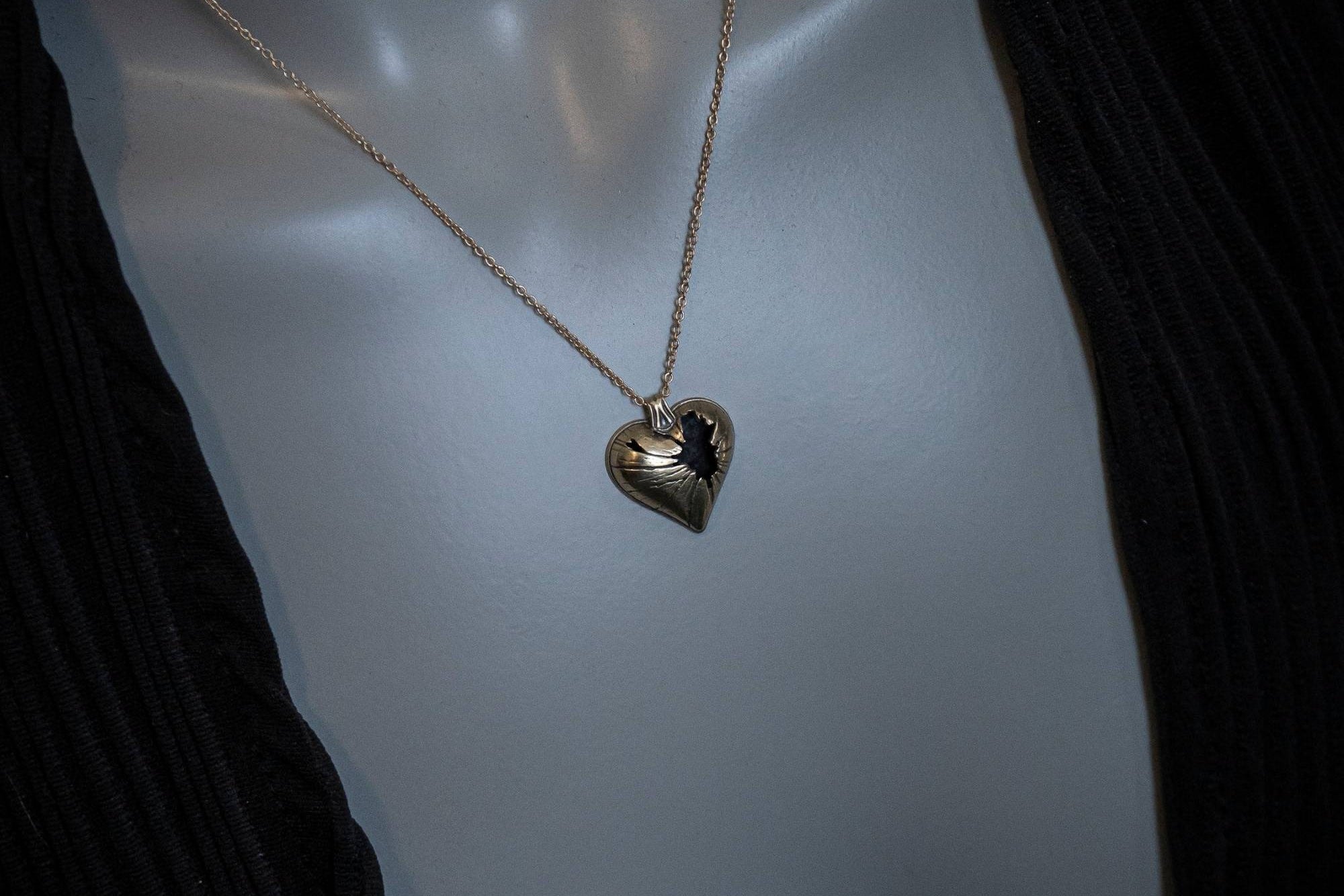 Heart-shaped pendant necklace on a mannequin with a dark background