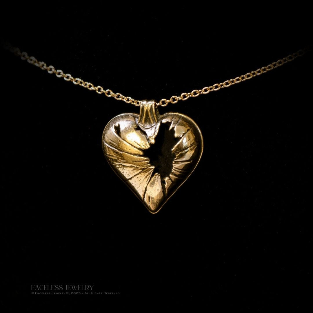 Gold heart-shaped pendant on a chain against a black background