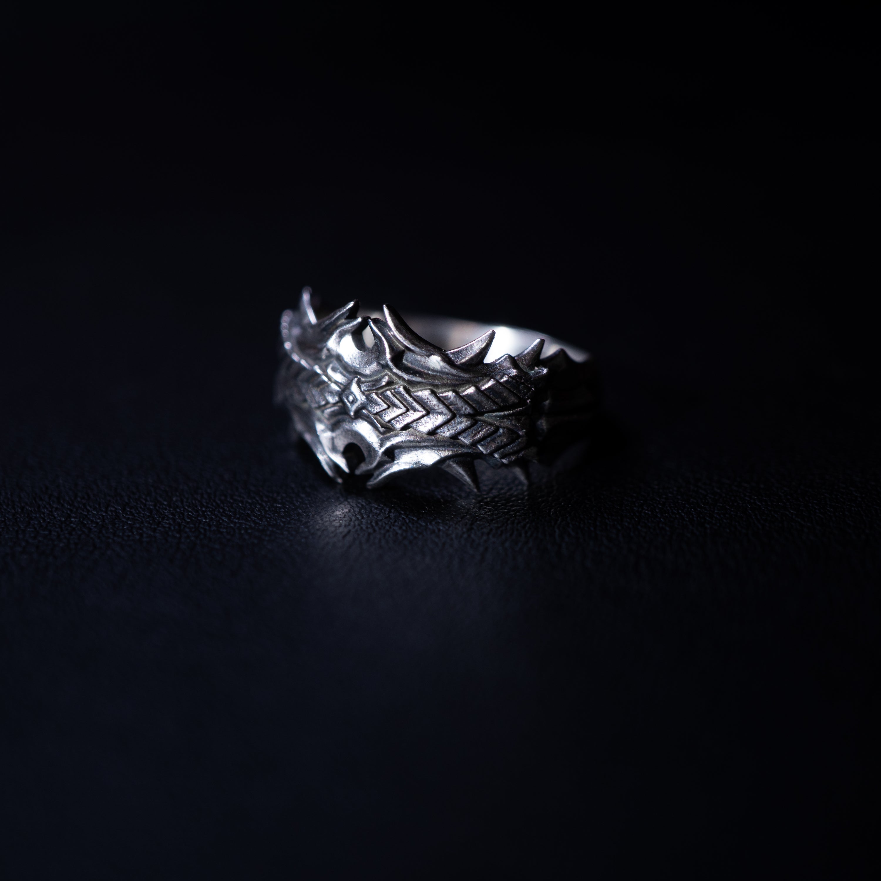 Silver ring with intricate design on a black background