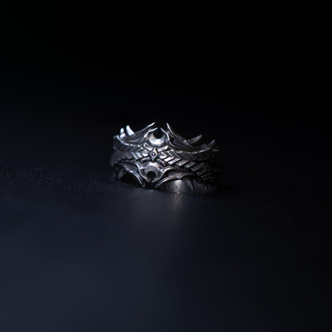 Silver ring with intricate design on a dark background