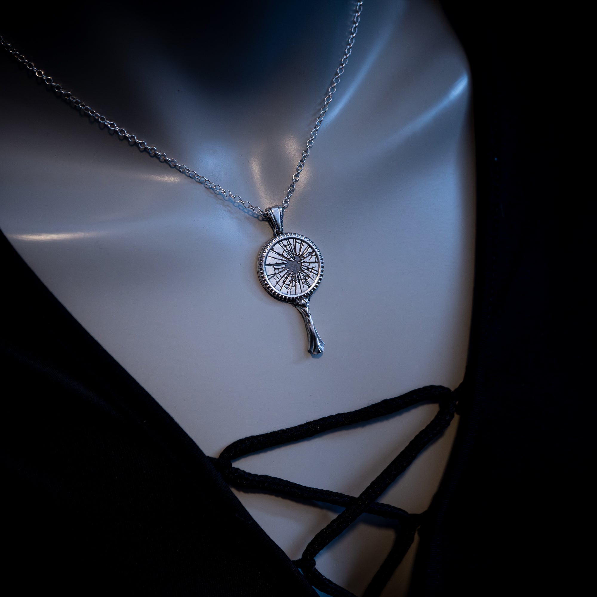 Necklace with a unique broken mirror pendant on a mannequin bust against a dark background
